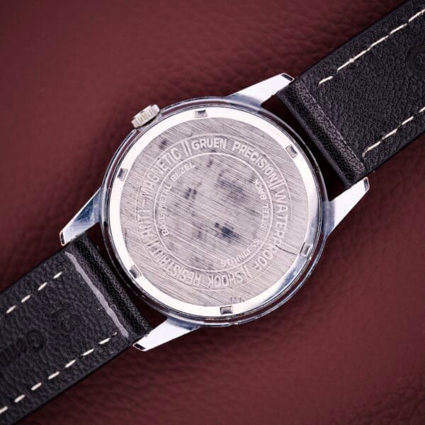 Back of a Gruen Precision Day / Date 522 RSS Sunburst Dial wristwatch with engraved details, displayed on brown textured leather. This timepiece features classic craftsmanship and the elegant Sunburst Dial design.