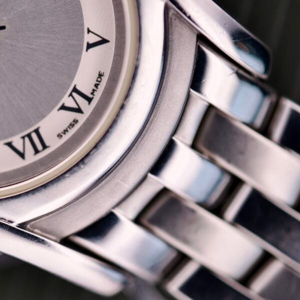 Close-up of a Gucci 5500L Stainless Steel Quartz wristwatch with metal band, Roman numerals V, VI, VII on the dial. Includes original box and papers.