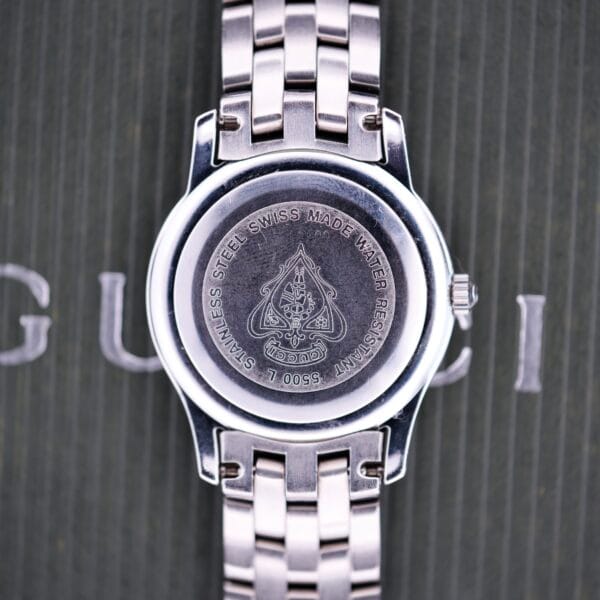 Gucci 5500L Stainless Steel Quartz watch showing engraved back, logo, bracelet, and case details; includes original Box & Papers.