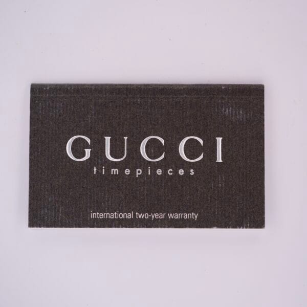 The Gucci 5500L Stainless Steel Quartz Box & Papers includes an international two-year warranty card with white text—ideal for collectors seeking authenticity and complete set.