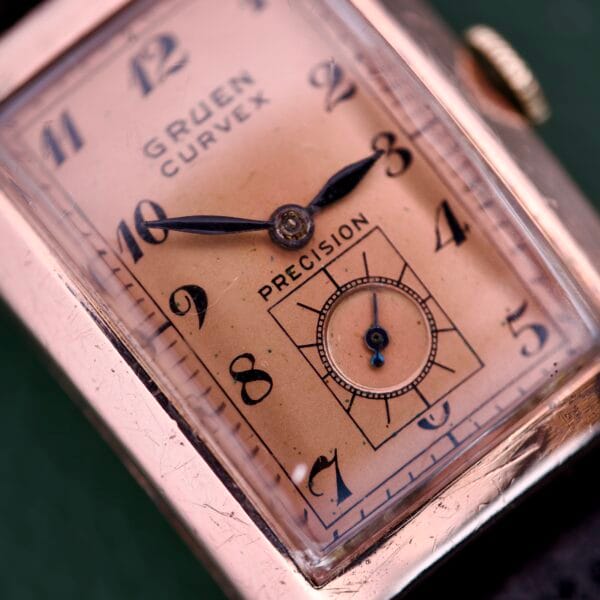 Close-up of a Gruen Curvex Precision Ref. 440-448 watch featuring a rectangular rose gold filled face with black numerals.