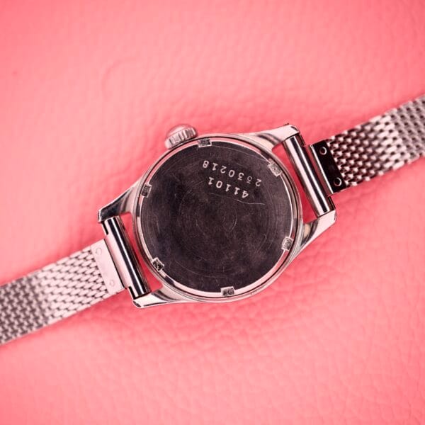 Ladies Certina Ref. 41101 in stainless steel with mesh band, Cal. 19-10, shown from the back on a textured pink background.