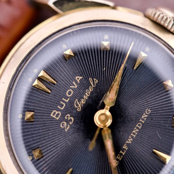 Close-up of a 1957 Bulova 23 Jewels Self Winding Cal. 10BPAC watch face with gold hour markers and 23 Jewels Self Winding text.