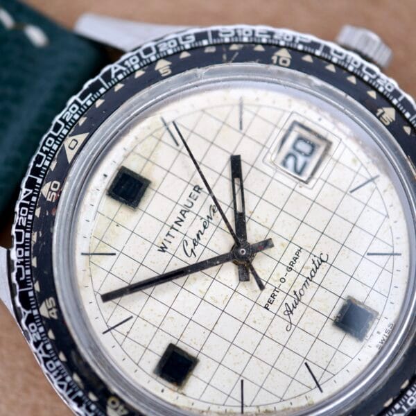 Close-up of a vintage Wittnauer Pert-O-Graph Ref. 7005 with grid-patterned dial, rare Pert-O-Graph Scale Bezel, and date display.