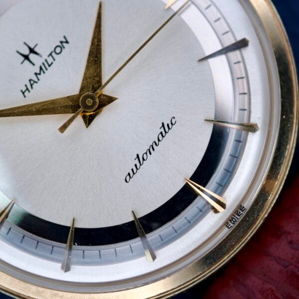 Close-up of a 1964 Hamilton Accumatic A-602 watch face with a silver chapter ring dial, gold hands and hour markers, powered by the precise Cal. 669 movement.