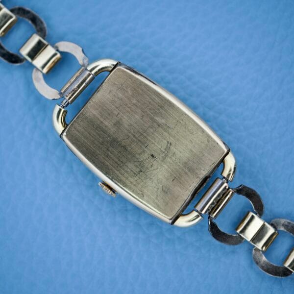 A vintage Bulova Art Deco wristwatch with a black dial and Arabic numerals (Cal. 10 AK) on a blue textured background.