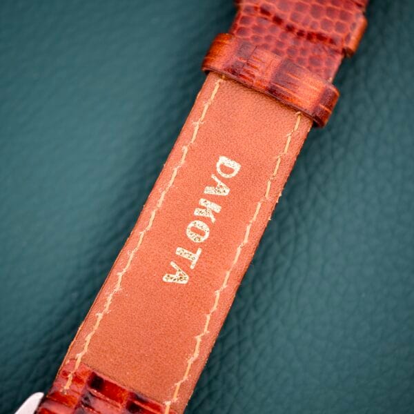 Brown leather watch strap with DANOTA embossed in gold on green textured background, designed to complement your Gruen Precision White Dial From France Cal. 515SS timepiece.