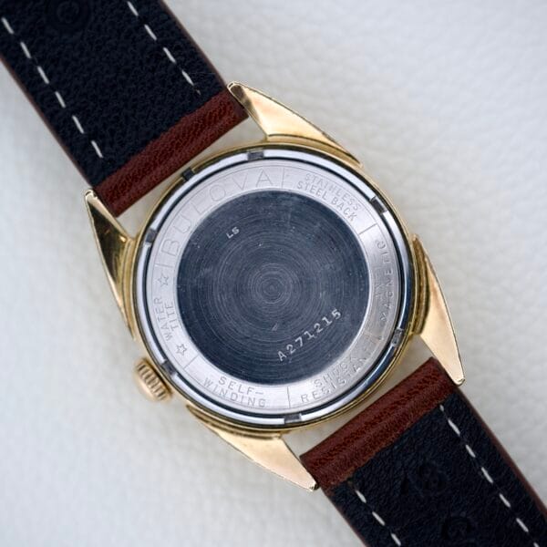 Back of a 1965 Bulova 23 Jewels Six Adjustments Automatic with black leather strap and engraved markings on the stainless steel case.