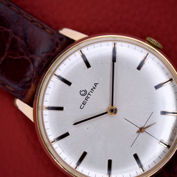 Close-up of a Certina Ref. 7400-207 watch with a brown leather strap and Rose Gold Tone case (Cal. 28-10) displayed against a red background.