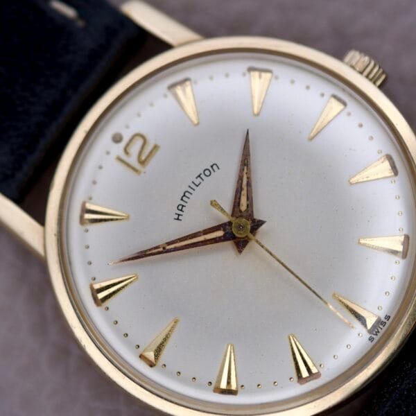 A close-up of a Hamilton Sea-Scape Sunburst Dial Manual Wind Cal. 671 wristwatch with gold hour markers and a black leather strap.