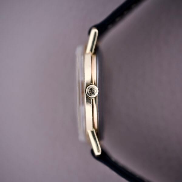Side view of the Hamilton Sea-Scape Sunburst Dial Manual Wind Cal. 671 gold wristwatch with a black leather strap, shown against a light background.