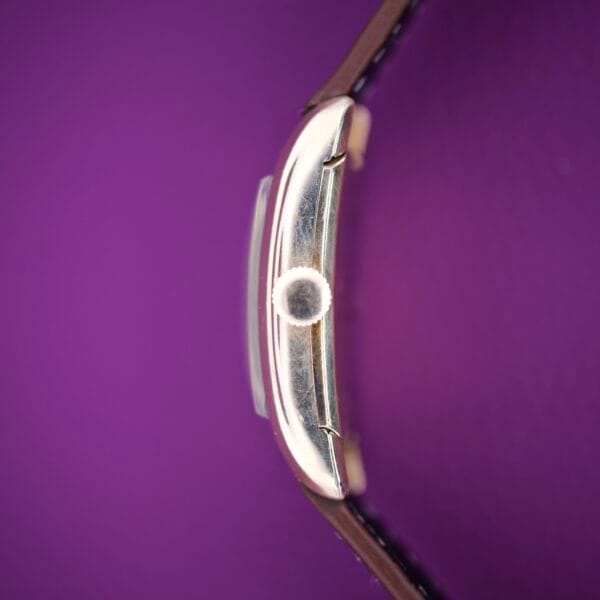 Side view of a 1936 Lord Elgin Star Dial Tank Style Case Manual Wind Grade 531 wristwatch with a brown strap on a purple background.