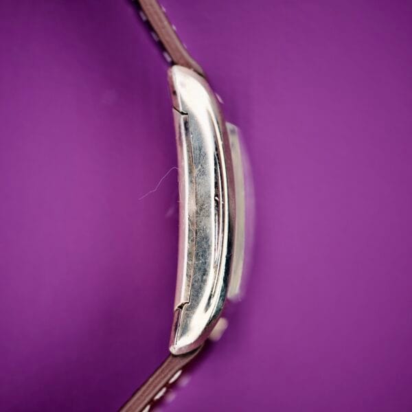 Close-up of the silver buckle on a brown strap of the 1936 Lord Elgin Star Dial Tank Style Case Manual Wind Grade 531, set against a vibrant purple background.