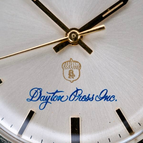 Close-up of a Rolex Presentation Watch Ref. 7002 featuring Dayton Press Inc., an acorn logo on a silver face, 14k Gold Filled details, and Cal. 1520 movement.
