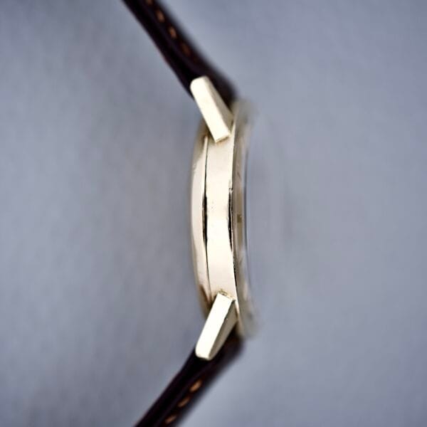 Side view of the Rolex Presentation Watch Ref. 7002 14k Gold Filled Cal. 1520, featuring a dark brown leather strap and set against a light background.