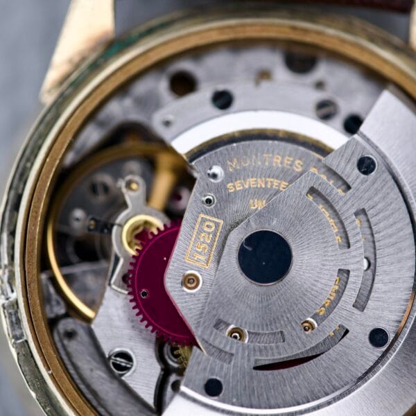 Close-up of the Rolex Presentation Watch Ref. 7002 in 14k gold filled, showcasing its Cal. 1520 movement with visible gears, screws, and engraved text—highlighting intricate detailing on this rare timepiece.