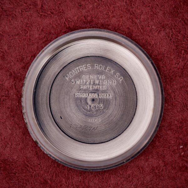Round metal watch case back engraved "Montres Rolex SA Geneva Switzerland," shown on red textured fabric—an authentic component from the Rolex Datejust 1603 Silver Dial Alpha hands.