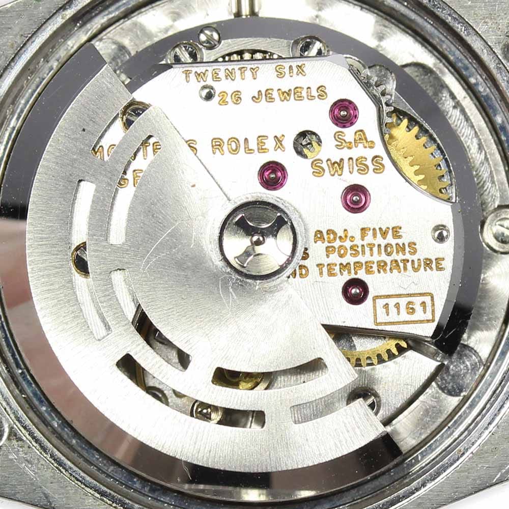 Close-up of a Rolex watch movement showing gears, jewels, and engraved text on the metal components.