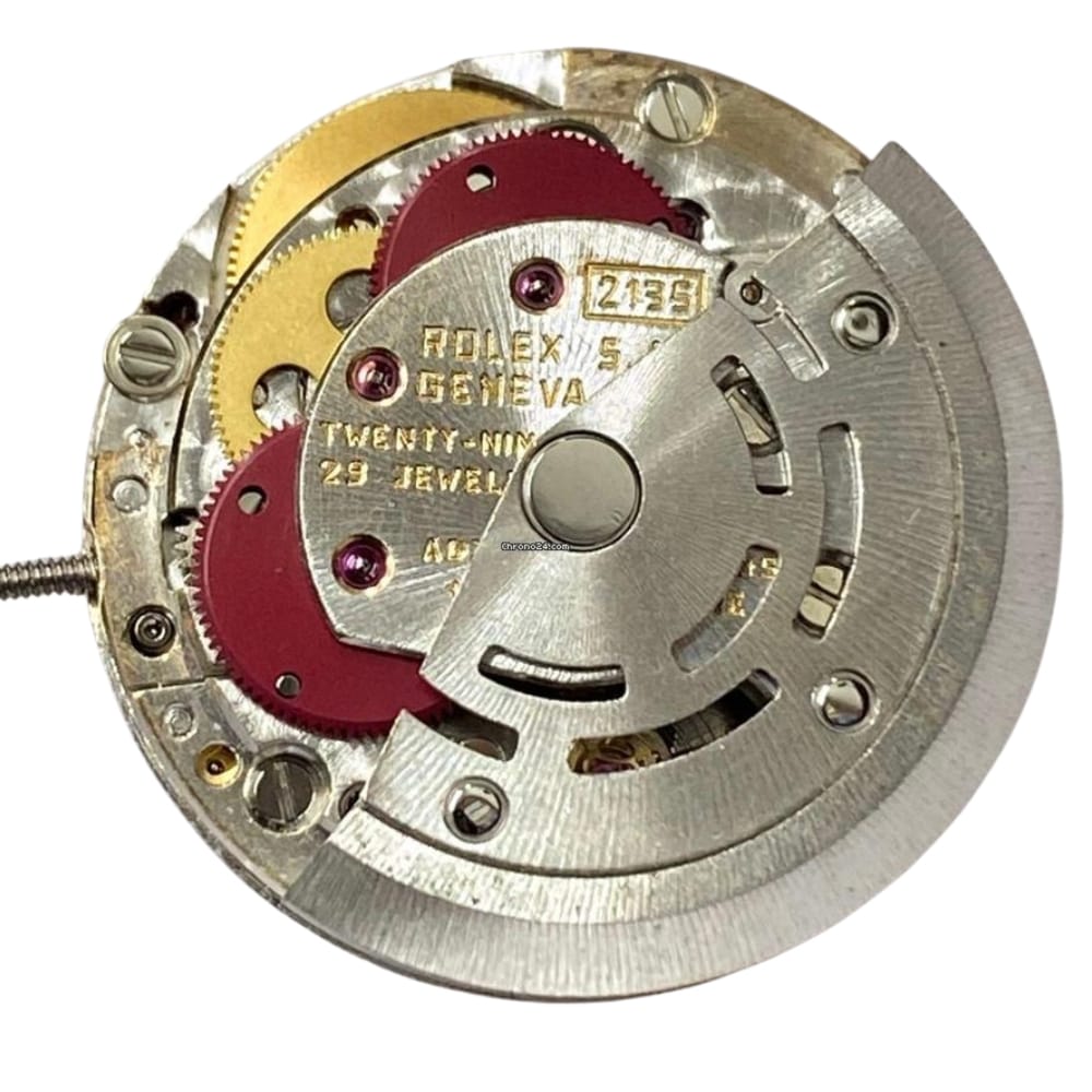 Close-up of a Rolex watch movement showing gears, red components, and engraved text.