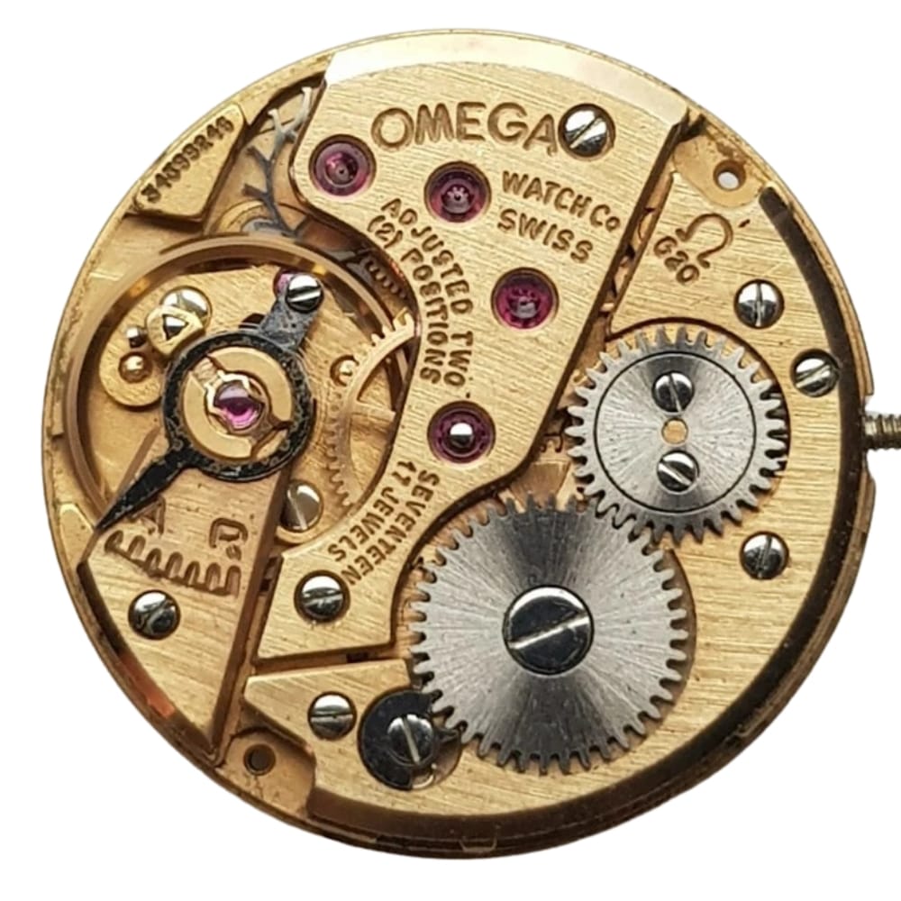 Gold Omega watch movement with visible gears, screws, and engraved text on the components.