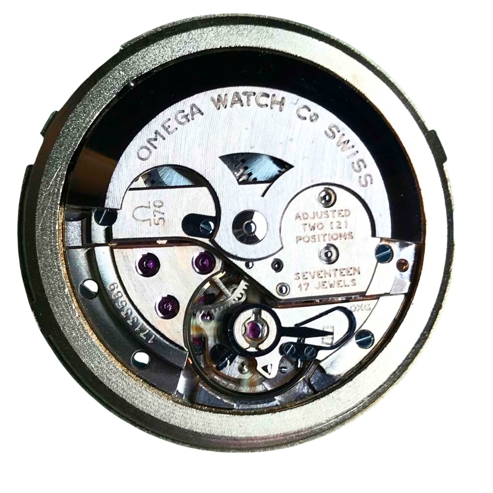 Close-up of an Omega watch movement showing gears and engraved text on the metal components.