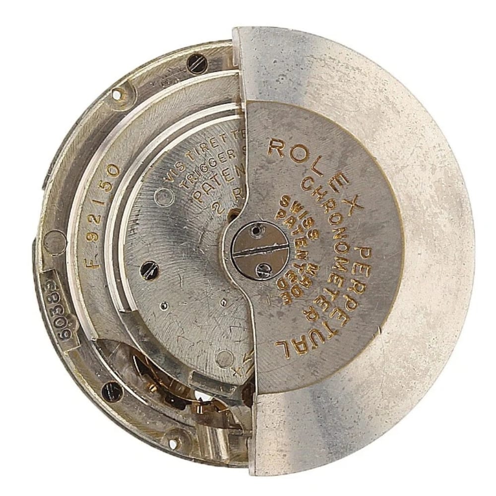 Close-up of a vintage Rolex watch movement with engraved text and visible gears.