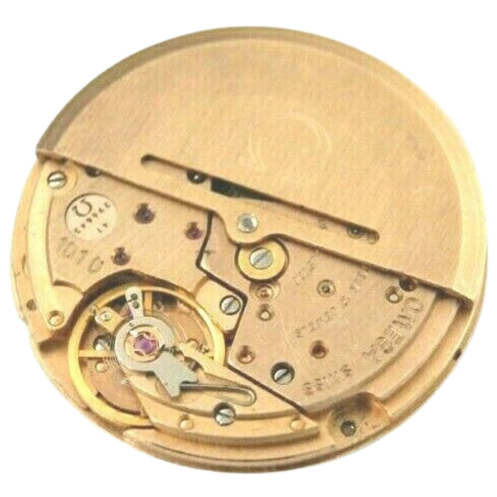 Gold-toned Omega watch movement with visible gears and mechanical components on a white background.