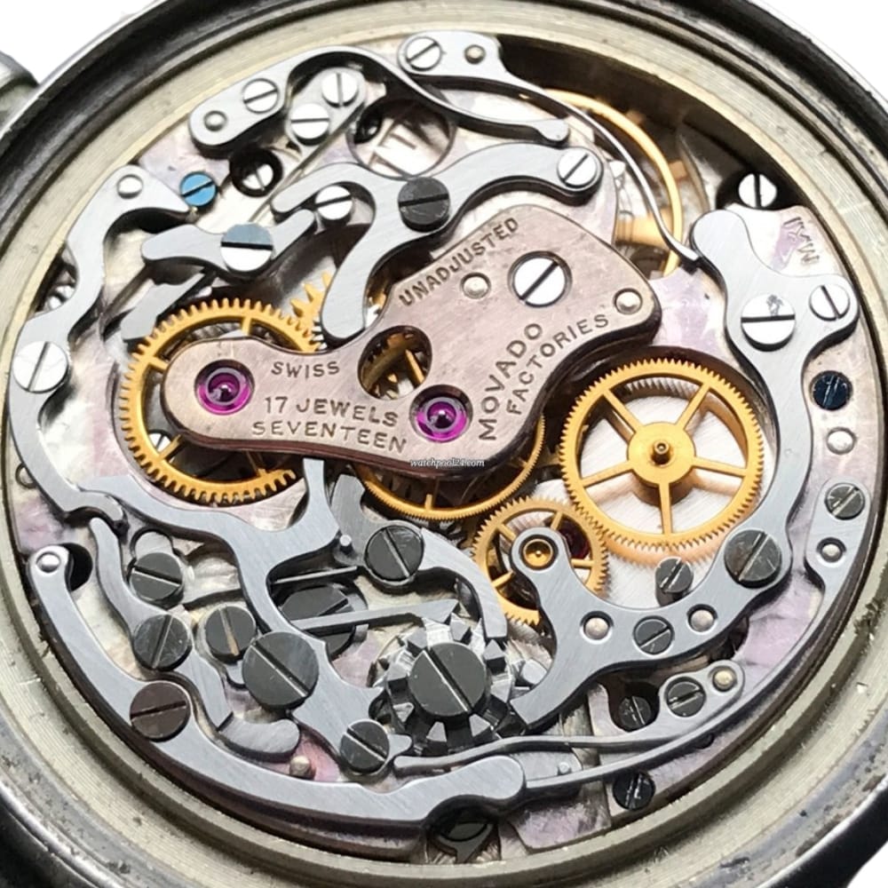 Close-up of intricate watch movement showing gears, levers, and the engraved words MOVADO FACTORIES.