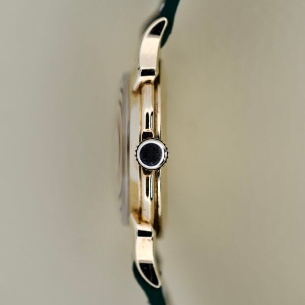 Side view of a Gruen Barclay "Spider" Ref. 335-723 gold wristwatch case with a black crown and dark strap, featuring 21 Jewels Cal. 335 for reliable performance.