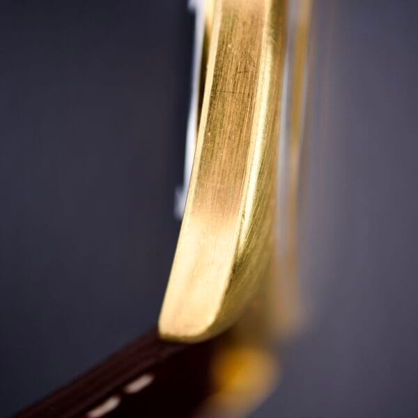 Close-up of the Bulova Cushion Case Automatic Ref. 7313-2 Cal. 11AOACD, featuring a gold edge and brown leather strap in a soft-focus macro shot, highlighting its refined details.