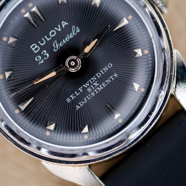 Close-up of a Bulova 23 Jewels Automatic Six Adjustments Cal. 10BPAC watch face, displaying the selfwinding and 23 jewels details.
