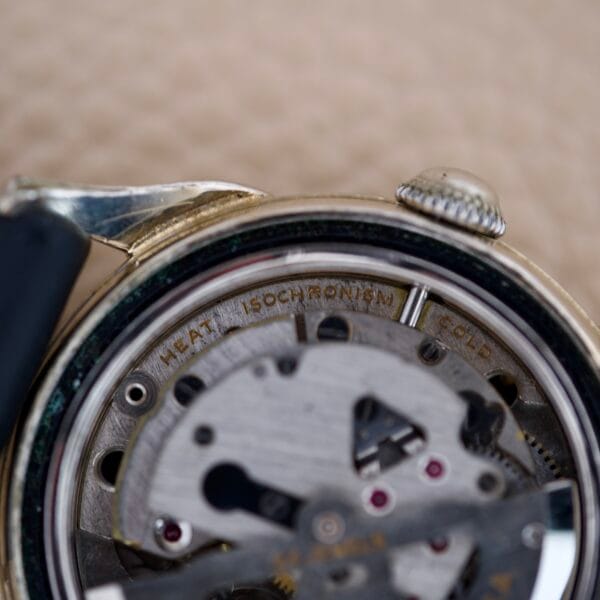 Close-up of a vintage Bulova 23 Jewels Automatic Six Adjustments Cal. 10BPAC watch movement, showcasing its intricate gears and engravings: HEAT | ISOCHRONISM | COLD.