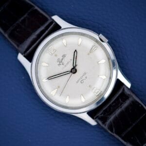 A Piguette Antioch 17 Jewels Manual Wind wristwatch with a stainless steel case rests on a blue textured surface.