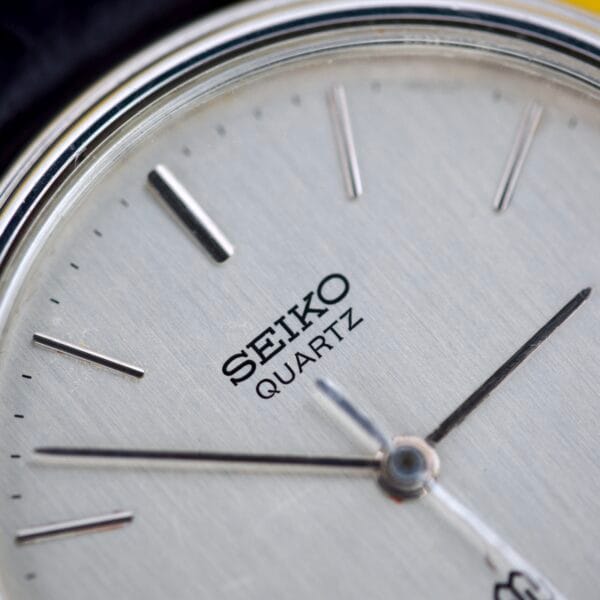Close-up of the Seiko Twin Quartz Ref. 9920-7000T Thin Stainless Steel watch face, showcasing the brand name, minimalist hour markers, and a sleek stainless steel case.