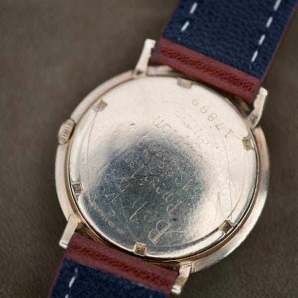 Close-up of the back of Finley's Nivada Grenchen Automatic White Dial, featuring engraved text and a navy blue leather strap.