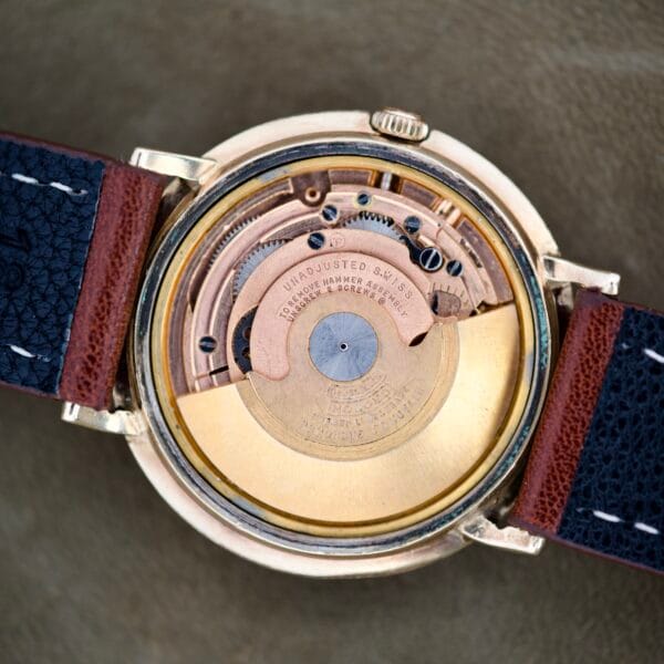Close-up of Finley's Nivada Grenchen Automatic White Dial, showcasing its exposed automatic movement and leather straps on both sides.