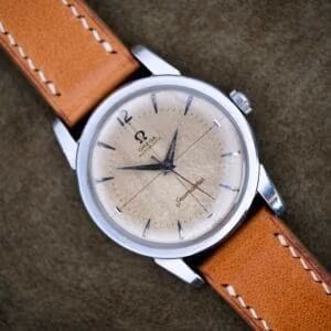 Omega Seamaster Automatic ref. 2846-1 SC on tan strap, cream tropical cross-hair dial against green backdrop.