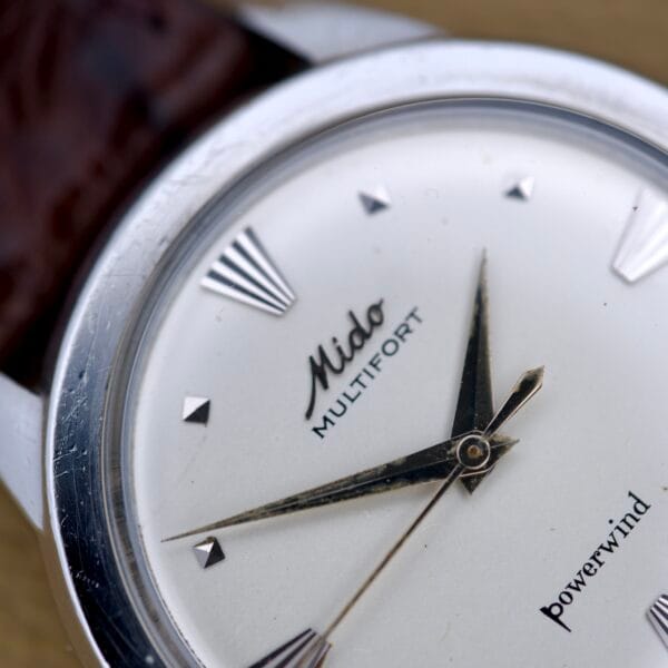 Close-up of a Mido Multifort Powerwind with white dial, Automatic Cal. 917P movement, and brown leather strap.