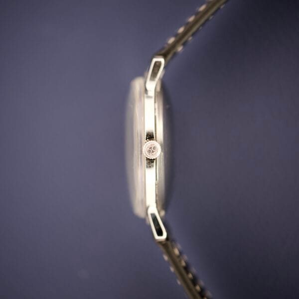 Side view of the Hamilton Accumatic X Sunburst Dial Stainless Steel Cal. 667 wristwatch with a metal band, displayed against a dark blue background.