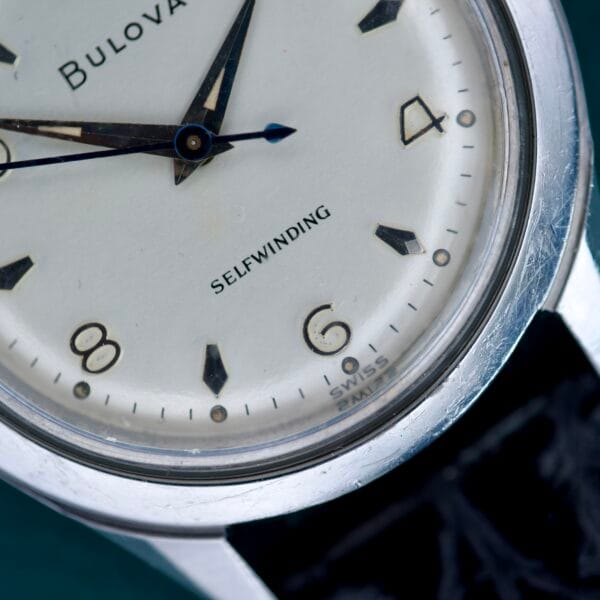 Close-up of a 1955 Bulova Automatic Stainless Steel Cal. 11ACAC wristwatch, featuring "Selfwinding" on the dial and detailed views of the numbers 2, 4, 6, and 8.