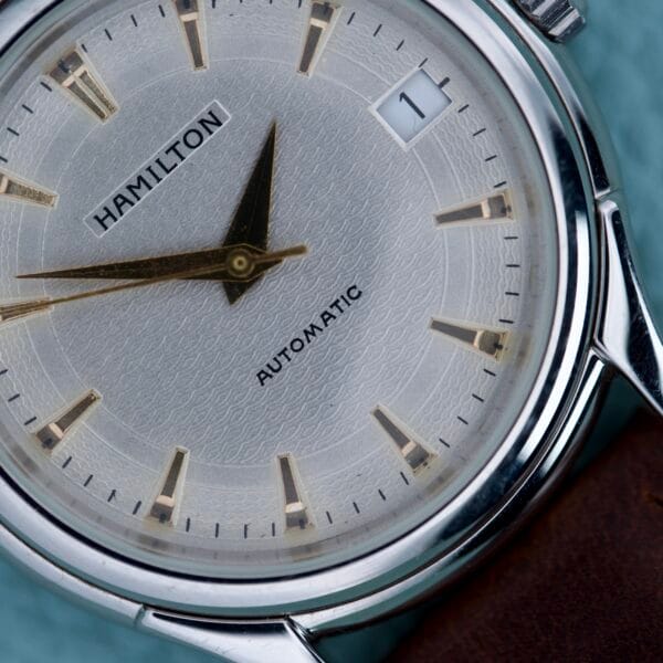 Close-up of the Hamilton Automatic Date Ref. 6239 in stainless steel, featuring a textured dial with date display and gold hour markers.