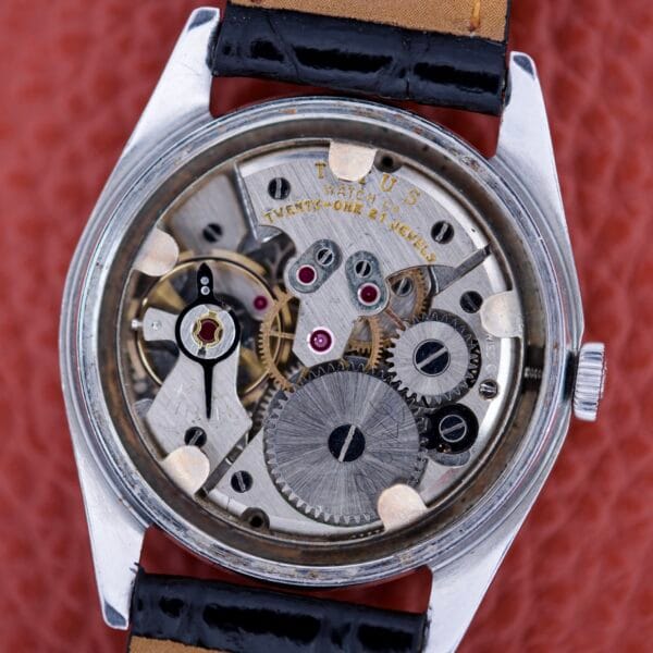 Close-up of a Titus De Luxe 21 Jewels Manual Wind watch with exposed gears and ruby jewels in a stainless steel case, featuring a leather strap.