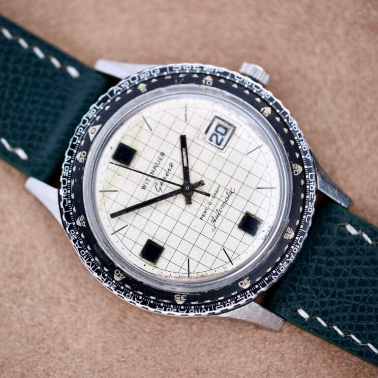 A vintage Wittnauer Pert-o-Graph wristwatch with a grid-patterned dial, black square hour markers, and a green leather strap.