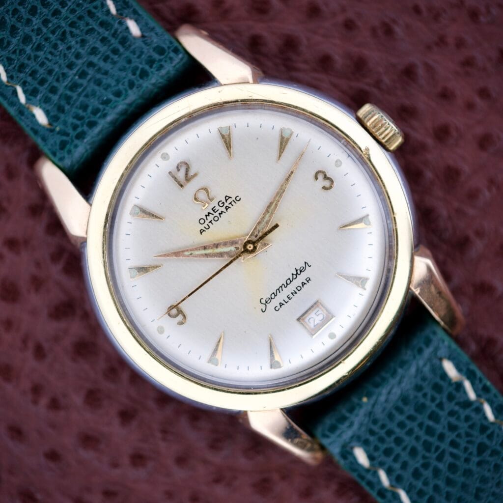 The Omega Automatic Seamaster Calendar Ref. 2627-4 Cal. 353 features gold hands, a teal strap, and a calendar date at 3 o’clock.