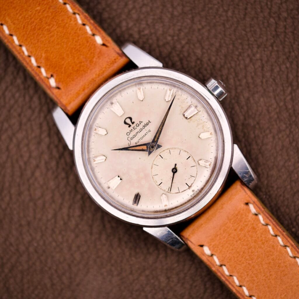 An Omega Seamaster Automatic Ref. 2848 Stainless Steel Cal. 490 with a tan leather strap displayed on a brown textured surface.