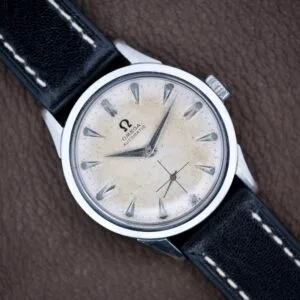 Omega Automatic Ref. 6040 with Arctic White Dial, silver markers, and black leather strap displayed on a brown surface. Stainless Steel Cal. 490 model.