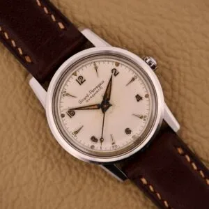 Girard Perregaux Gyromatic in stainless steel with automatic Cal. 47BF 620, featuring a brown leather strap, displayed on a beige textured background.