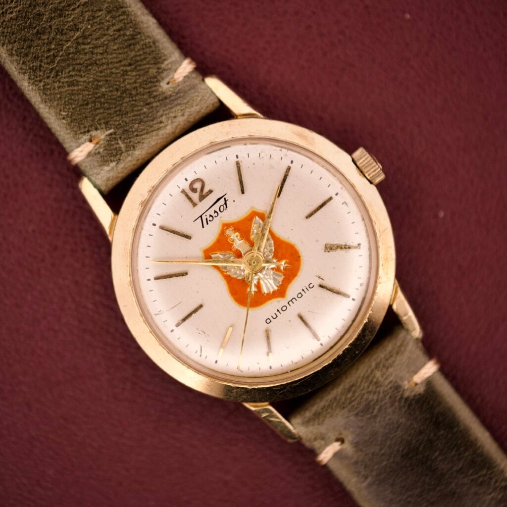 A Tissot Automatic Presentation Watch 10k GF featuring an emblem dial and worn leather strap.