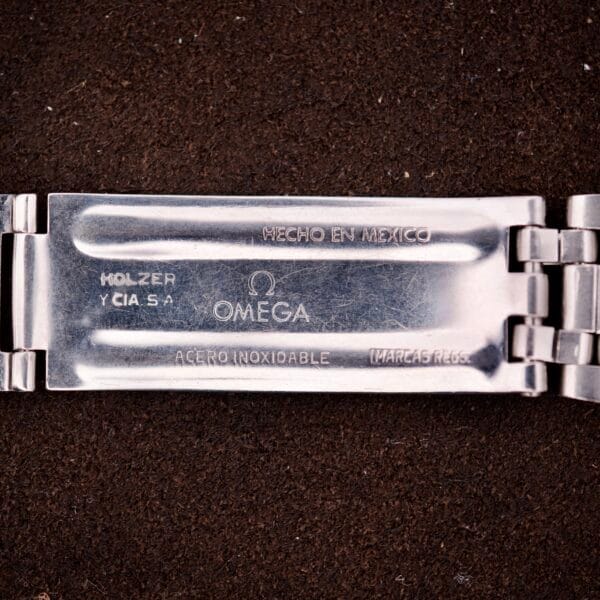 Close-up of an Omega Seamaster Speedsonic F300 Ref. 188.0002 chronograph clasp with Spanish date on original bracelet, shown against a dark textured background.