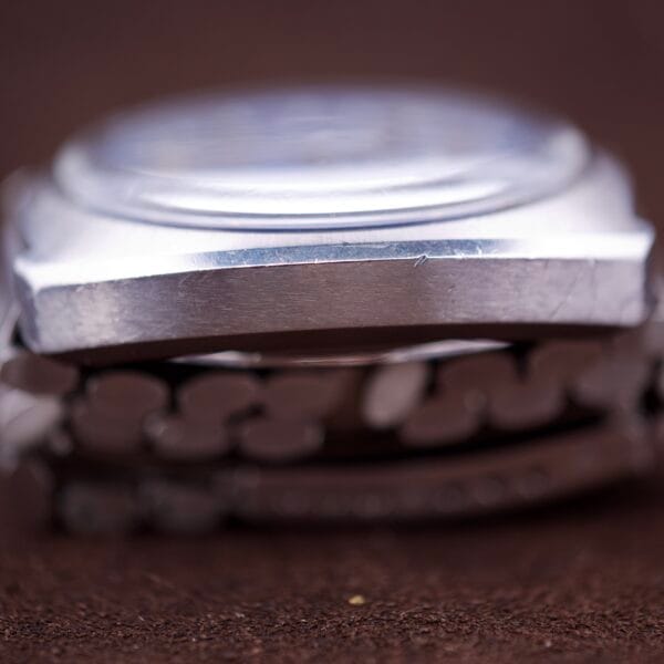 Close-up side view of an Omega Seamaster Speedsonic F300 Ref. 188.0002 Chronograph wristwatch with original bracelet and Spanish date display, set against a brown background.